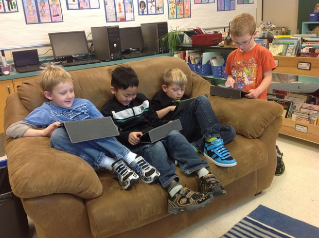 Crianças mexendo em iPads no sofá
